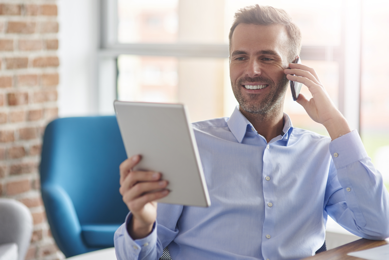 man-talking-phone-browsing-digital-tablet