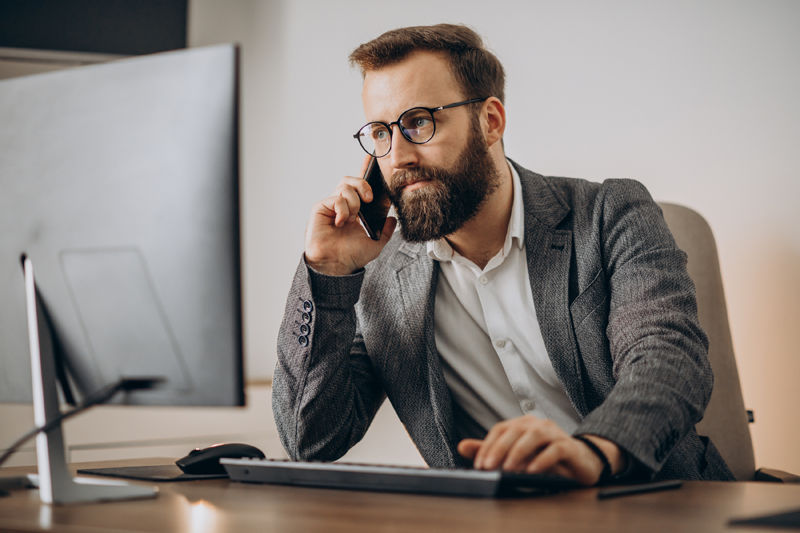 young-business-man-talking-phone-working-computer
